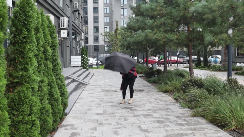 Asian woman trying to hold her umbrella in strong wind in winter.