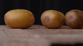 4K video of kiwi fruit being cut, filmed against a black background with the camera moving slowly