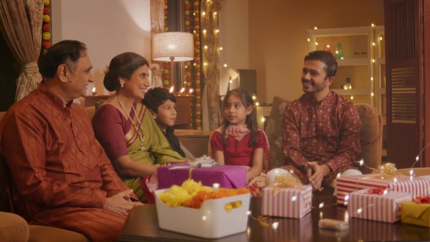 A Happy smiling Hindu ethnic Indian pretty woman or housewife in traditional clothes serving sweets (Laddoos, Laddus) to the family members on the occasion of Diwali festival in a well decorated home. Royalty-Free Stock Footage #1095189559