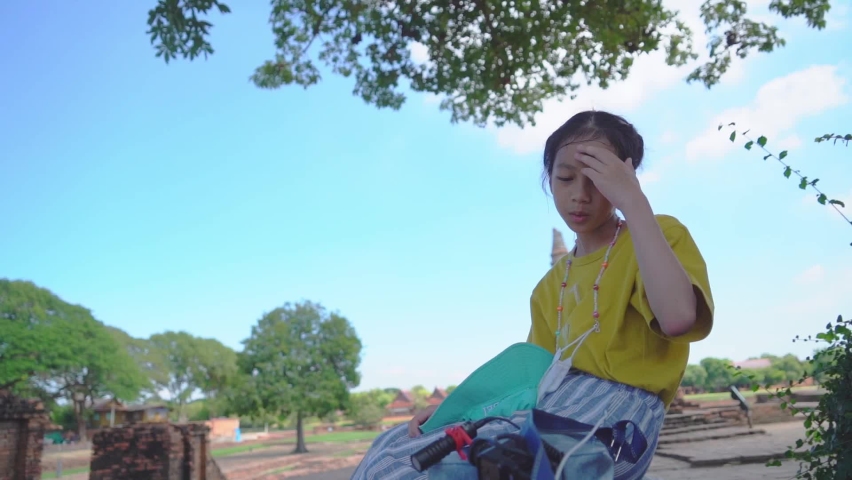 Girl sitting in Ayutthaya ruin while traveling in Thailand.
