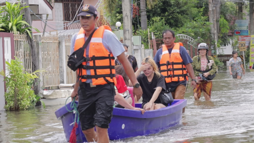People carrying their belongings to escape the flood., Meng District, Thailand, on October 3, 2022, is a photograph from real flooding. With a slight color adjustment
