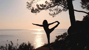 Young woman practicing Utthita Hasta Padangusthasana yoga pose outdoors on the hill near the sea. Hand to big toe pose, stretching out upwards and sidewards while standing on one leg.  - Powered by Shutterstock - Get 15% off with code: PIKWIZARD15