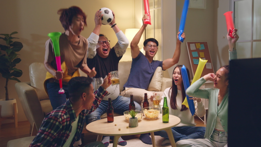 Happy Asian people with friends watching soccer or football on tv and celebrating victory at home, world cup football cheering concept | Shutterstock HD Video #1095194937