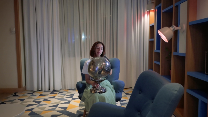 Woman sitting on a chair and rotating the Earth globe. 4k footage UHD 3840x2160 