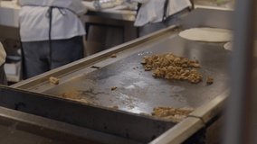 This video shows meat and tortillas being cooking on a restaurant flat top stove.