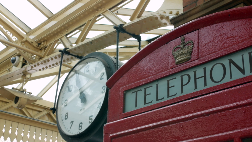 Intage clock and red telephone box at a British railway train station in London England. Establishing shot. | Shutterstock HD Video #1095211007