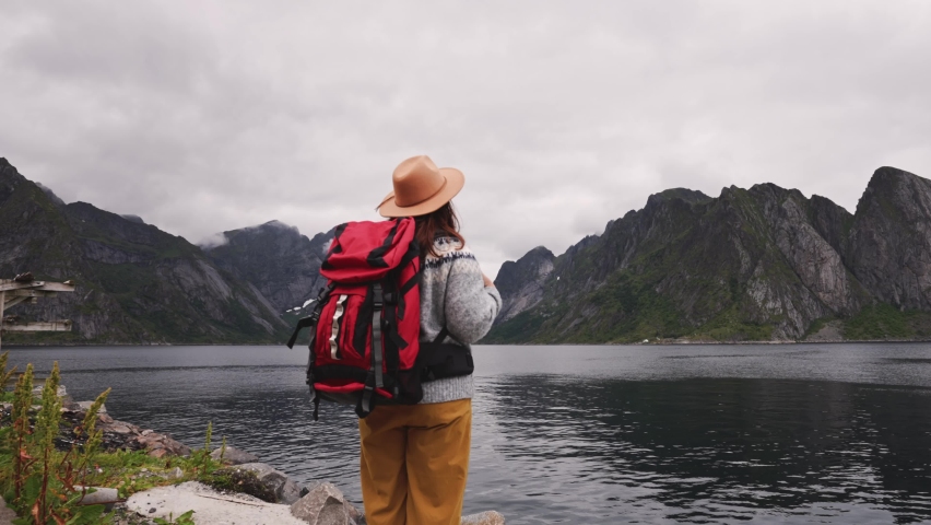 Happy woman tourist in Lofoten islands in Norway, mountains and sea background