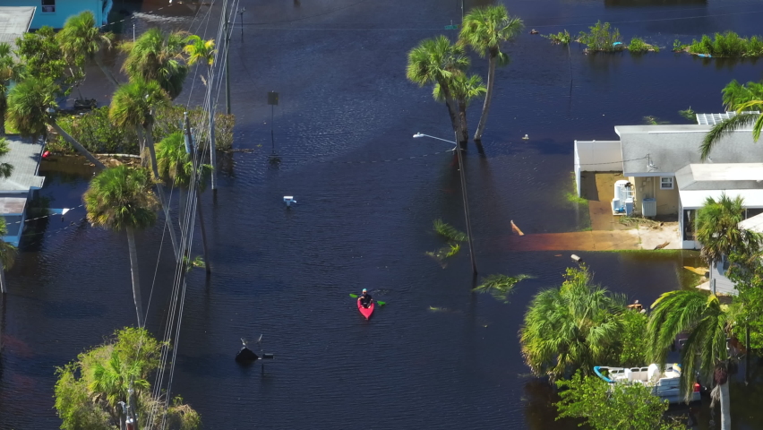 Kayak boat floating on flooded street surrounded by hurricane Ian rainfall flood waters homes in Florida residential area. Consequences of natural disaster
