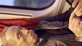  Elderly man travels in a train and uses a smartphone in the morning time, Vertical video