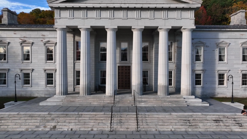 Rising aerial shot of the Vermont State House. Fall colors on trees revealed behind gold dome on Capitol.