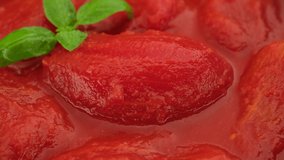 Whole peeled tomatoes and basil leaf, covered with tomato juice. Italian food ingredient