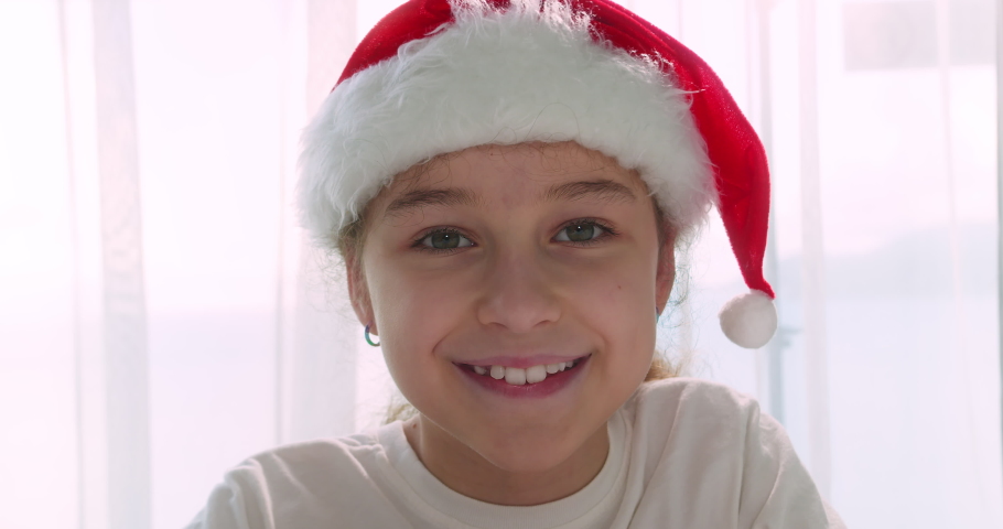 Portrait happy smiling cute child in Christmas hat Santa Clausa. Portrait beautiful happy little girl, child looks in camera.
