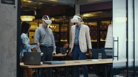 Multi-ethnic office workers testing VR headsets together, using tablet computer and wireless controllers, watching data, working in modern office of hi-tech company. Cyberspace digital technology - Powered by Shutterstock - Get 15% off with code: PIKWIZARD15