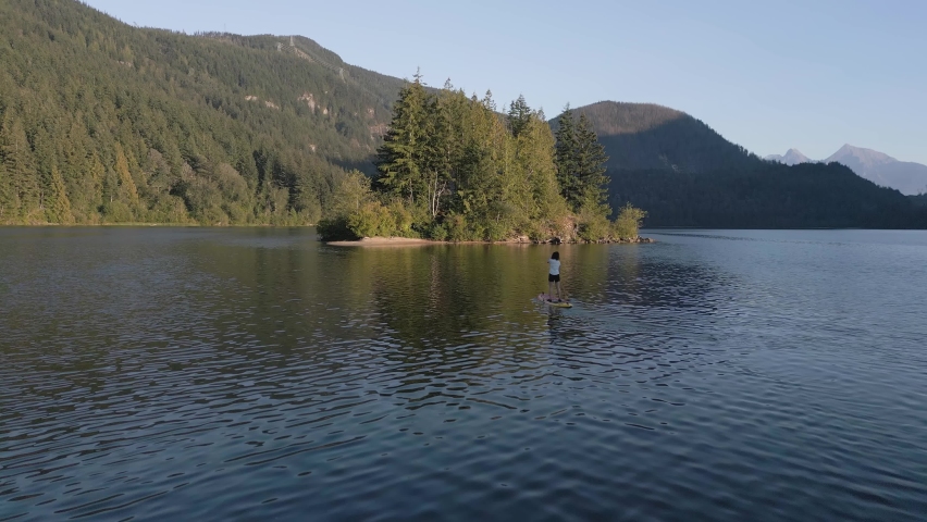 Adventurous Woman Paddling on a Paddle Board in a peaceful lake. Sunny Sunset. Hicks Lake, Sasquatch Provincial Park near Harrison Hot Springs, British Columbia, Canada. Slow Motion