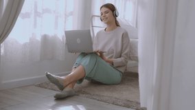woman enjoys working and music with her laptop on the bed