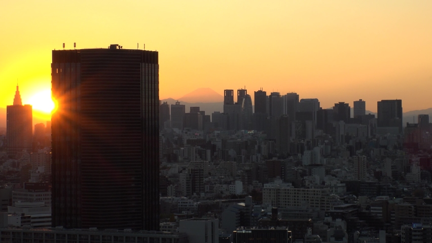 TOKYO, JAPAN : Aerial high angle sunset CITYSCAPE of TOKYO and MOUNT FUJI. View of buildings around Shinjuku. Long time lapse shot, dusk to night. Japanese urban metropolis and nature concept video.