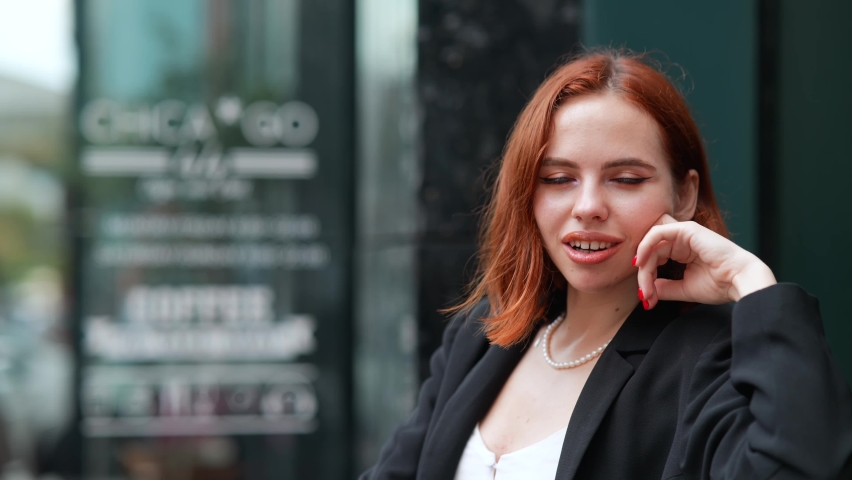 Female looking at camera while talking sitting in sidewalk cafe
