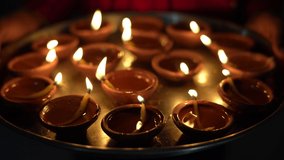 Beautiful Diwali Greeting using Diya or clay oil lamp lit and arranged over Rangoli made by multi coloured rice grains, selective focus