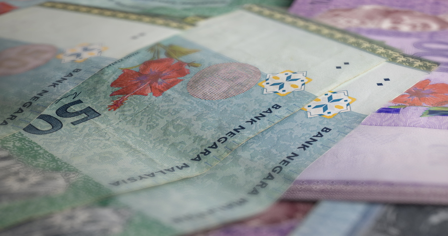 A big pile of Malaysian Ringgit. A large amount of 50 and 100 ringgit banknotes. Stack of  banknotes of Malaysia. RM 50 unsorted on a table.  Money with red hibiscus flower and the King of Malaysia | Shutterstock HD Video #1095250343