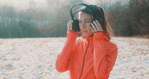 Close-up portrait Run Woman, headphone girl runner on the snow in winter sunny day. Female in pink sportswear jacket fitness training outdoors, healthy lifestyle and vitamins, 4K slow motion video