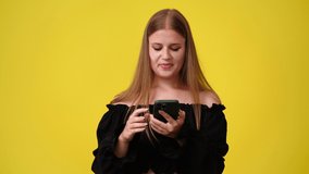 4k video of woman with phone on yellow background.