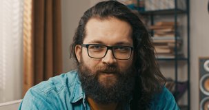 A man in bearded glasses talks to a family friend via camera, a remote meeting. The boy talks about his new job, hobbies. Contact with relatives at a distance.