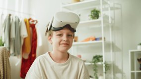 Boy gamer portrait, using virtual reality glasses with controllers, playing video games, child wearing new generation gaming headset for entertainment and education at home, future technology concept.