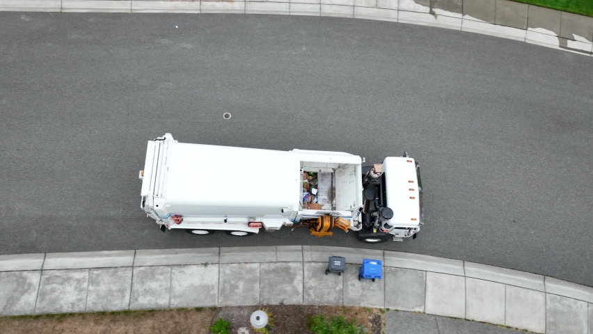 Top down view of a waste facilities truck as it loads recycling from the curb into its payload. Royalty-Free Stock Footage #1095278519