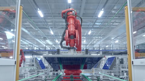 Orange Industrial Robot Arm Moving Solar Panels at Production Line at Modern Bright Factory. Solar Panels are being Assembled on Conveyor. Automated Manufacturing Facility. POV view from the Line 库存视频