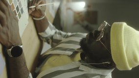 Vertical close up shot of African American male designer listening to music, using color palette and drawing picture in copybook while working on creative project at night - Powered by Shutterstock - Get 15% off with code: PIKWIZARD15