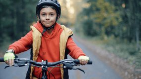 4K kid riding on mountains bike in the forest. Boy in helmets cycling on the autumn nature trail. Active smiling child on bike. - Powered by Shutterstock - Get 15% off with code: PIKWIZARD15