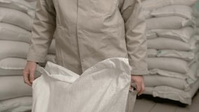 a man opens a white bag with a knife. against the backdrop of a large warehouse with full bags - Powered by Shutterstock - Get 15% off with code: PIKWIZARD15