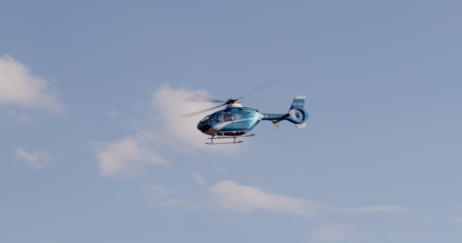 Movement helicopter in blue sky inscription on the board of police. Helicopter surveillance for public safety. Aerial policing ensuring community security. Patrol chopper maintains aerial vigilance.