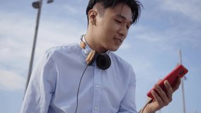 Close up of an excited Asian boy using smartphone and laughing. Funny people communicating with digital device chatting outdoors. New concept of socializing on social media, millennial generation - Powered by Shutterstock - Get 15% off with code: PIKWIZARD15