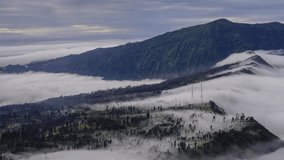 4K Timelapse of moving cloud over a village at Mount Bromo. Tilt Down effect