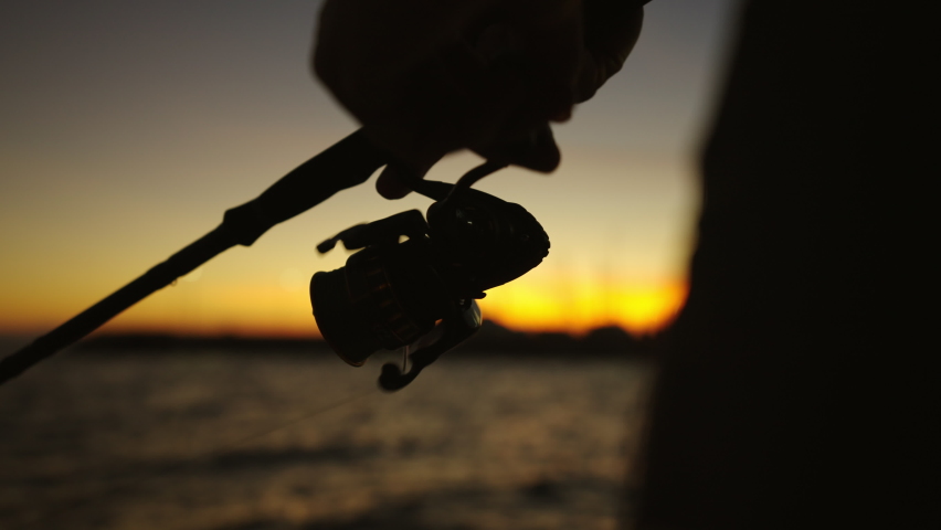 Fisherman holding fishing rod with reel close-up. Angler with rod, spinning wheel on the sea. Man catches fish on the river Royalty-Free Stock Footage #1095312277