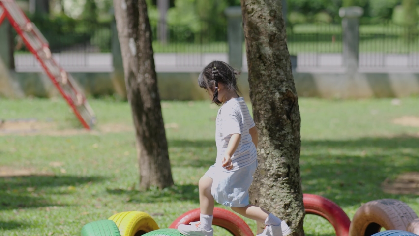 Cute asian girl smile play on school or kindergarten yard or playground. Healthy summer activity for children. Little asian girl climbing outdoors at playground. Child playing on outdoor playground. Royalty-Free Stock Footage #1095314611