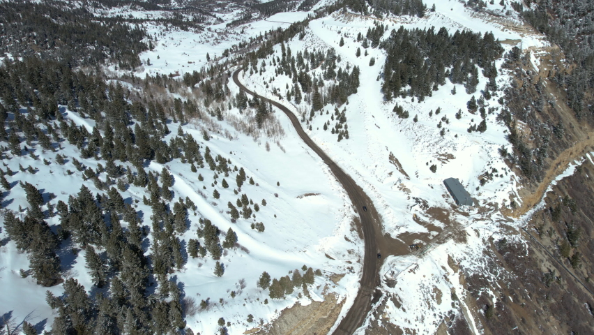 Aerial View of Dark Vehicle on Mountain Pass and White Winter Landscape on Sunny Day. Douglass Pass, Book Cliffs, Colorado USA