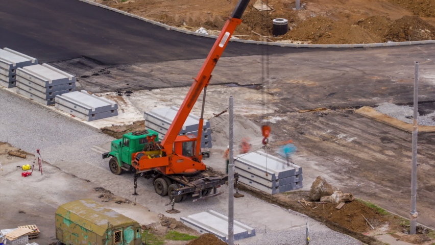 Installing concrete plates by crane at road construction site timelapse. Industrial workers with hardhats and uniform. Reconstruction of tram tracks in the city street. Aerial top view from above Royalty-Free Stock Footage #1095318623