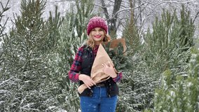 Young beautiful cheerful woman with a bouquet of Christmas tree branches on a background of green Christmas trees during a snowfall. - Powered by Shutterstock - Get 15% off with code: PIKWIZARD15