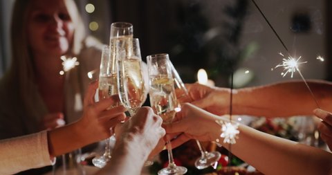 The family clinks glasses over the festive table, holds sparklers in their hands Video Stok