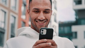 Joyful happy african latino man freelancer american guy stand on city street hold modern phone texting message make internet order search online media news distance communication use digital service - Powered by Shutterstock - Get 15% off with code: PIKWIZARD15