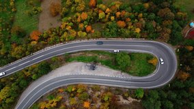 Aerial view of a winding road in the Carpathians in autumn. Beautiful autumn landscape with colorful trees. Atmospheric drone video. Beautiful nature and villages in Romania