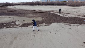Drone shot of a boy running on the sand. The sea in autumn. Cold weather.