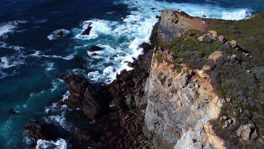 Natural Aerial drone shot flying over Big Sur California coast beach. The ocean clouds sky sun sunny waves crashing. Travel view scene peak weather wave. Rocky formations. High quality 4k footage.