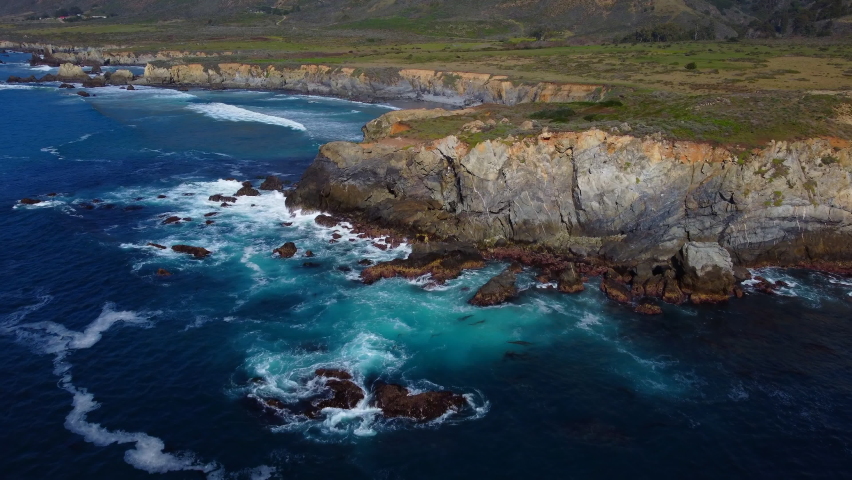 Aerial drone flying over Big Sur California coast beach. The ocean clouds sky sun sunny waves crashing. Travel view scene weather wave. Rocky formations. High quality 4k footage.