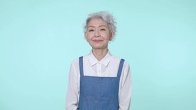 Talking Asian senior woman wearing an apron.