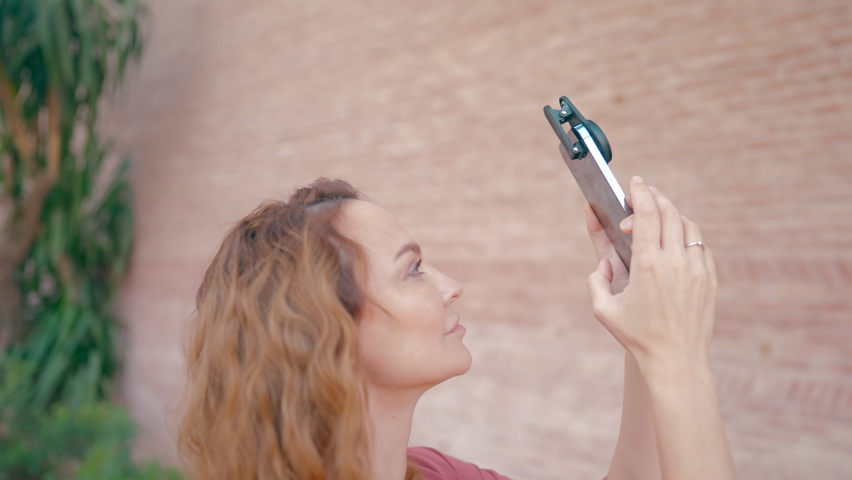 Beautiful young woman shooting a video. Action. A beautiful woman with long hair who shoots videos on an iPhone 13 pro with amazing accessories on it. | Shutterstock HD Video #1095361679