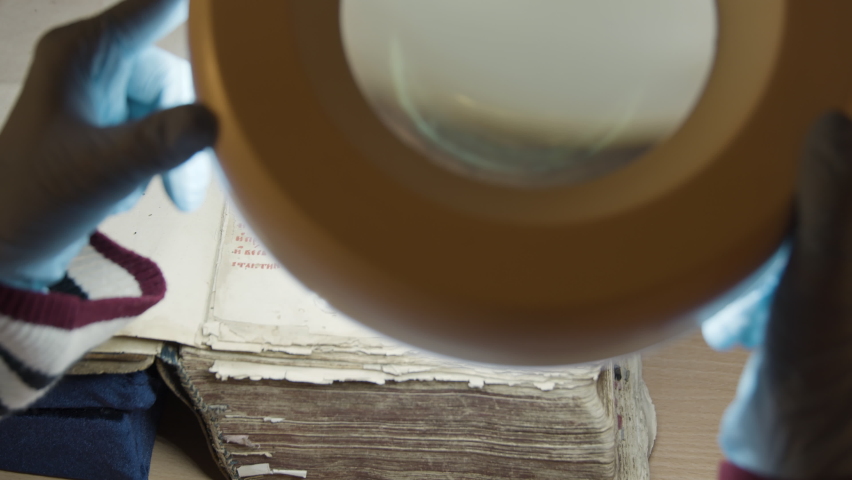 A large magnifying glass lamp that shines on an old letter. Stock footage.An old paper covered with Old Russian letters in the archive, which is examined by experts.