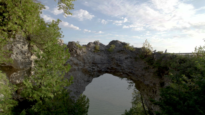 Aerial footage of Arch Rock as the camera flies over the arch a bird flies off into the distance.